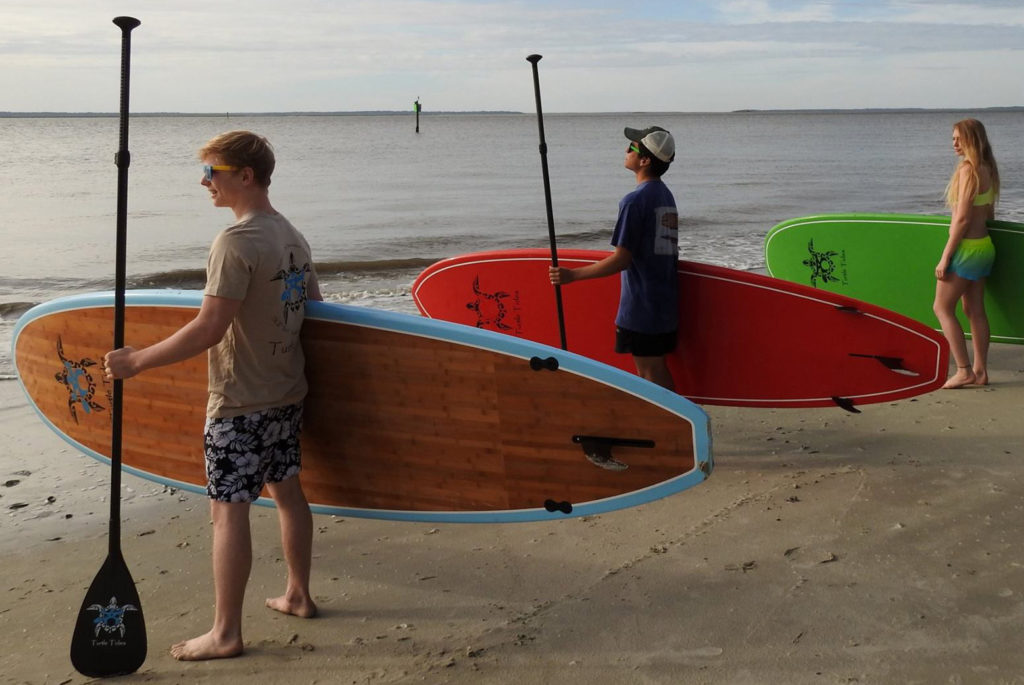 Picture of kids ready to hit the water on their Turtle Tides paddle boards. 
